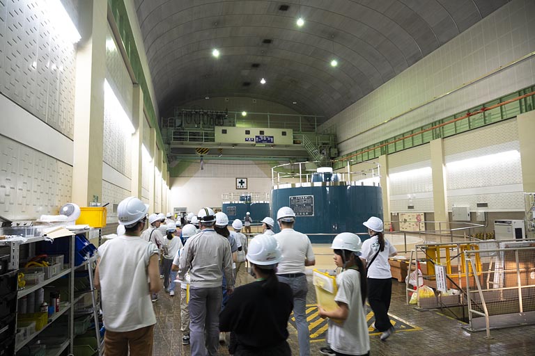 全員ヘルメットを被り、安全第一で見学開始。搬入路トンネルを通って発電機室に到着 発電機室では大きな発電機が稼働していました